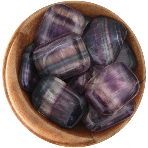 Bowl of polished Rainbow Fluorite slices. Cut into rectangles with curved corners. Stones have multi-colored stripes, which include purple, yellow, green, blue, and/or white.