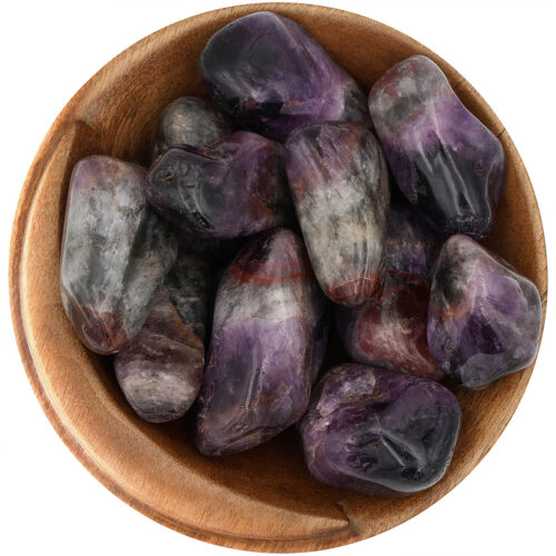 Bowl of polished Super Sevens. Irregular shaped stones, polished smooth, with multiple colors on each stone, mainly purple, green, and red.