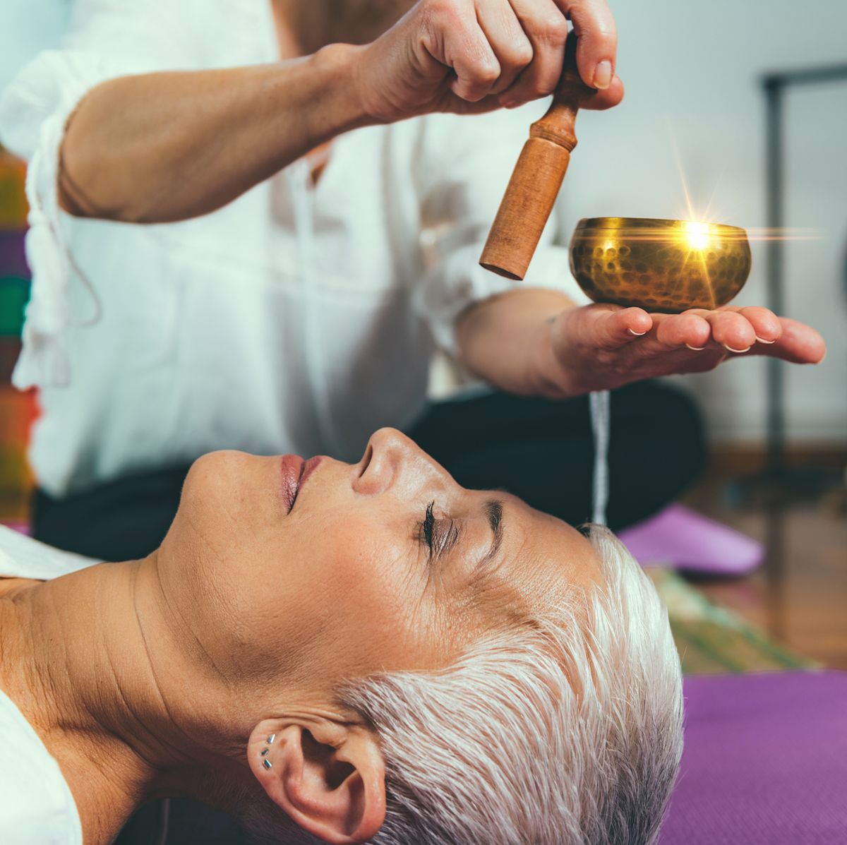 Woman singing bowl Older woman lying down, listening to a metal singing bowl played in the background